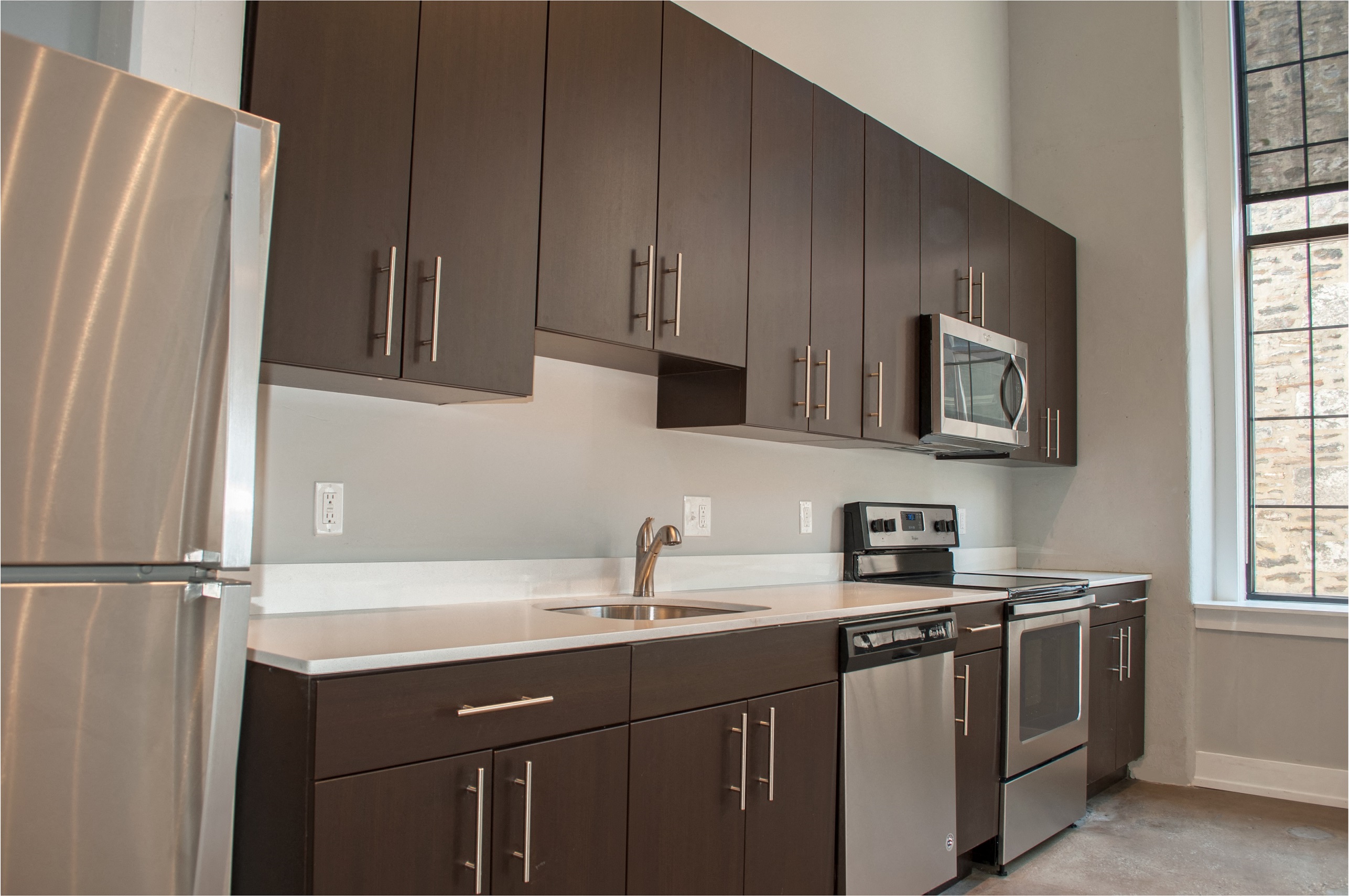 A kitchen with brown cabinets and a stainless steel refrigerator.