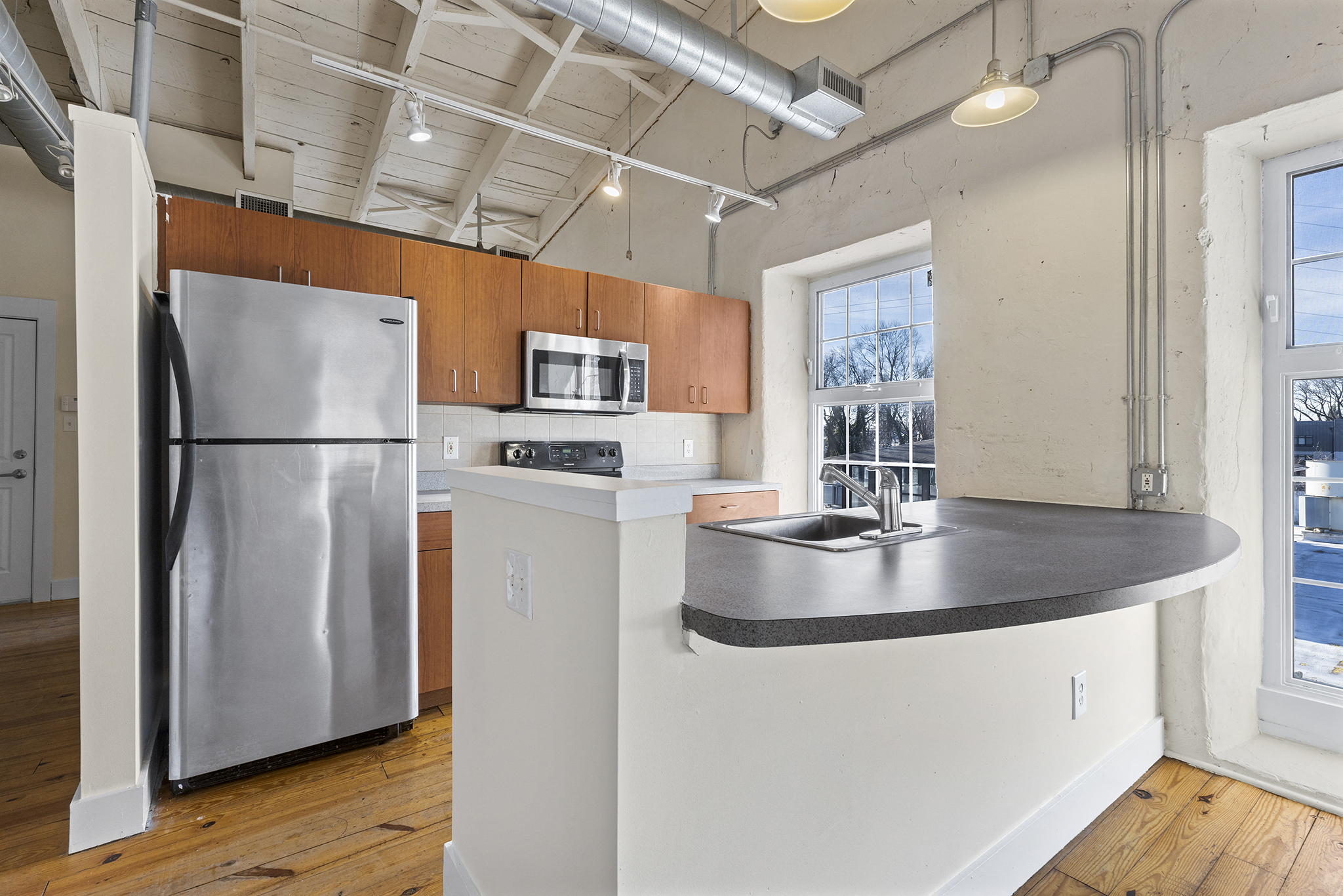 A kitchen with a stainless steel refrigerator and a microwave above the counter.