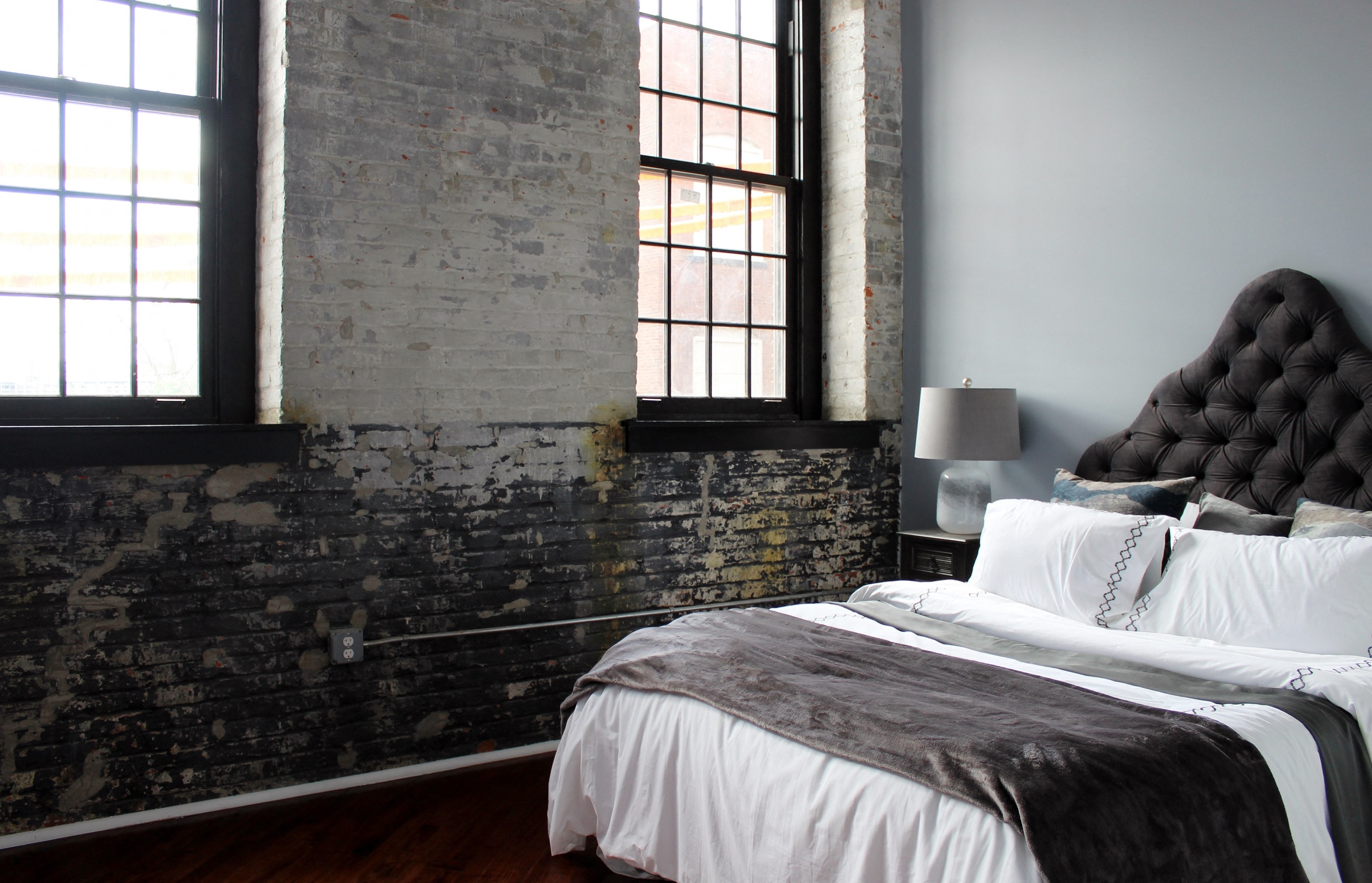 A bedroom with a large bed and a brick wall.