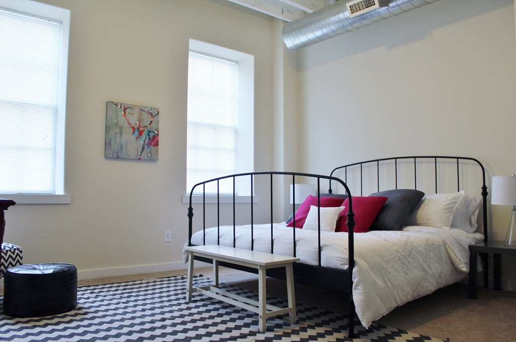 a bedroom with a bed and a black and white checkered rug