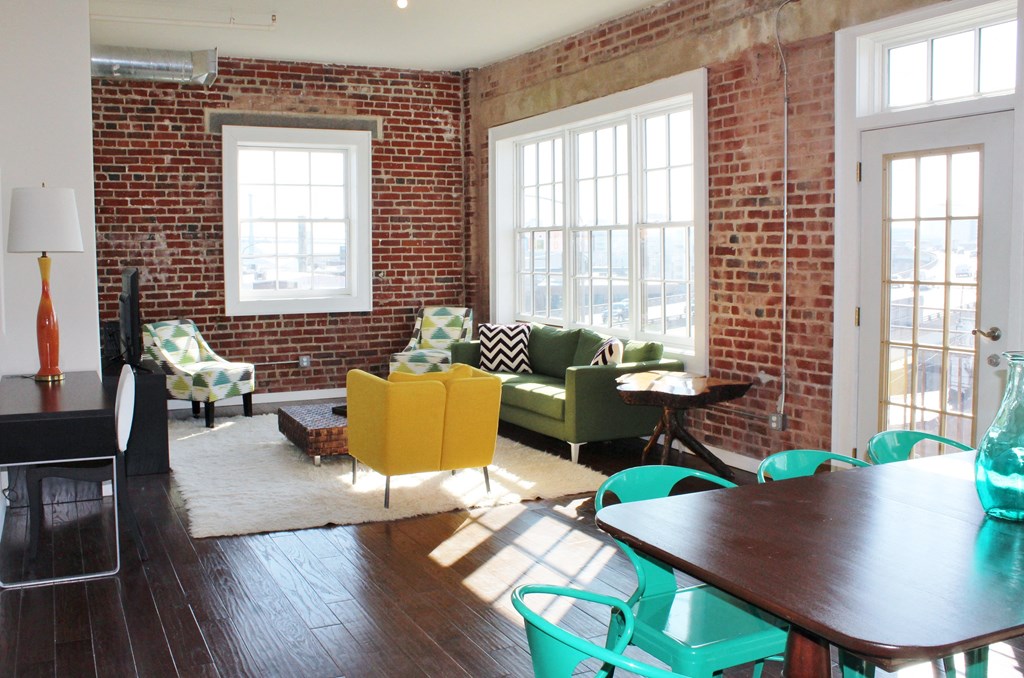 a living room with a table and chairs and a brick wall