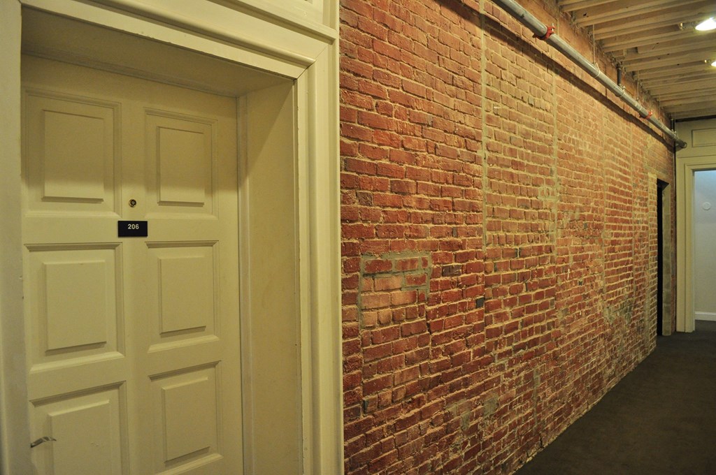 a brick wall in a hallway with a white door