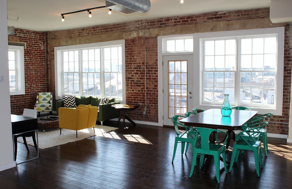 a living room with a table and chairs and a brick wall