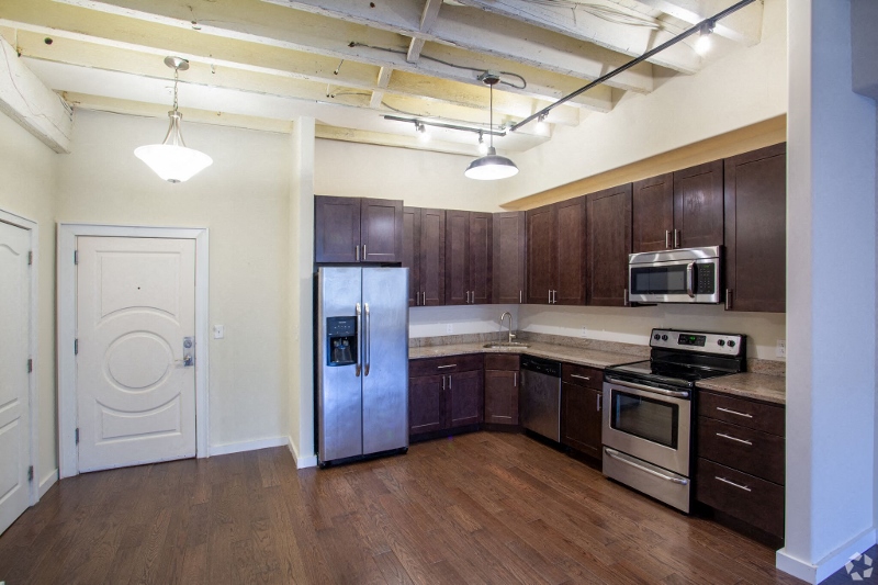 an empty kitchen with wooden floors and stainless steel appliances