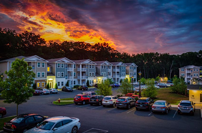 a sunset over an apartment complex with cars parked in a parking lot