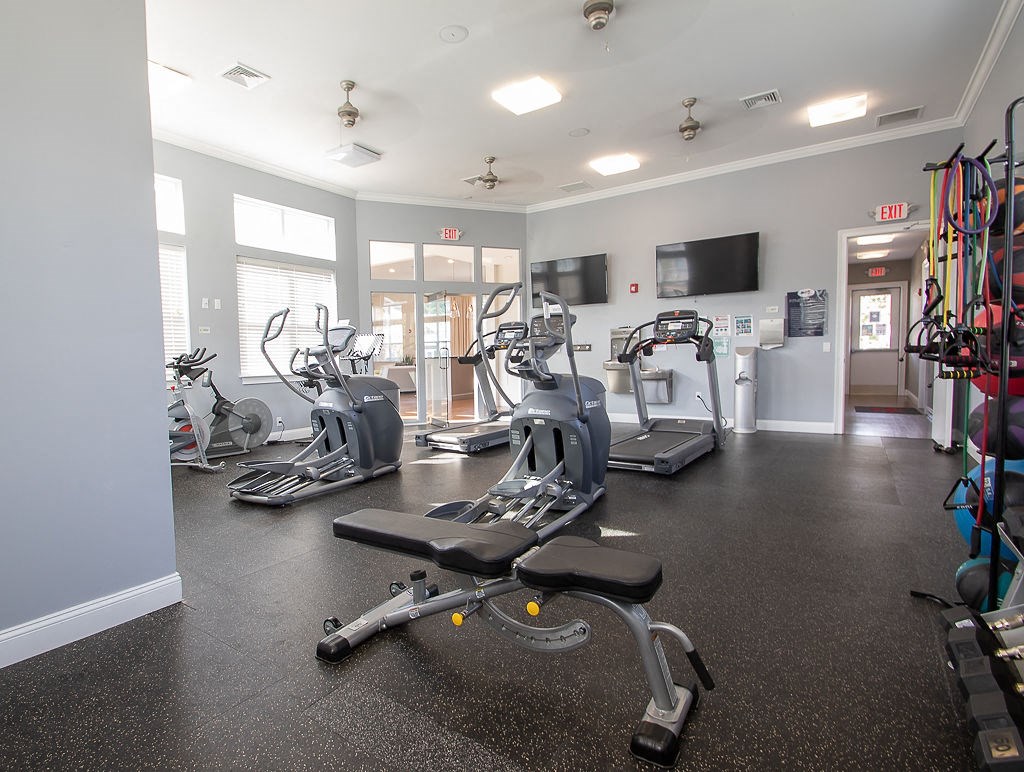 a gym with cardio machines and a tv