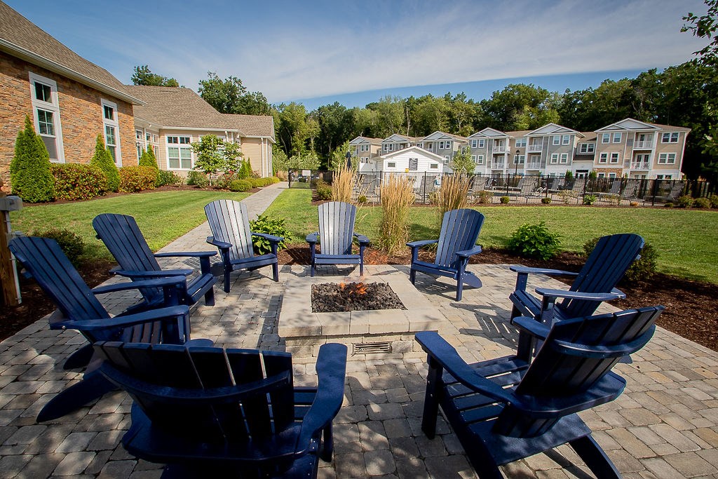 an outdoor patio with blue chairs and a fire pit