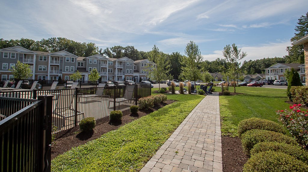 an exterior view of an apartment complex with a walkway and lawn