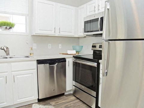 A modern kitchen with white cabinets and stainless steel appliances.