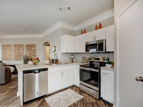 A modern kitchen with white cabinets and stainless steel appliances.