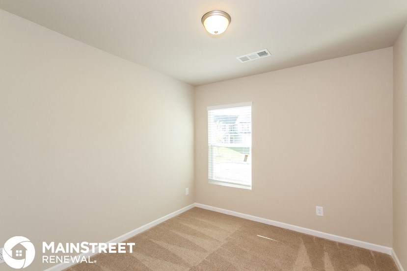 the spacious living room with a large window and carpeted flooring