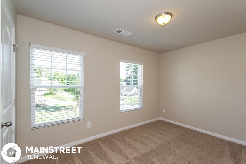 a bedroom with two windows and a carpeted floor