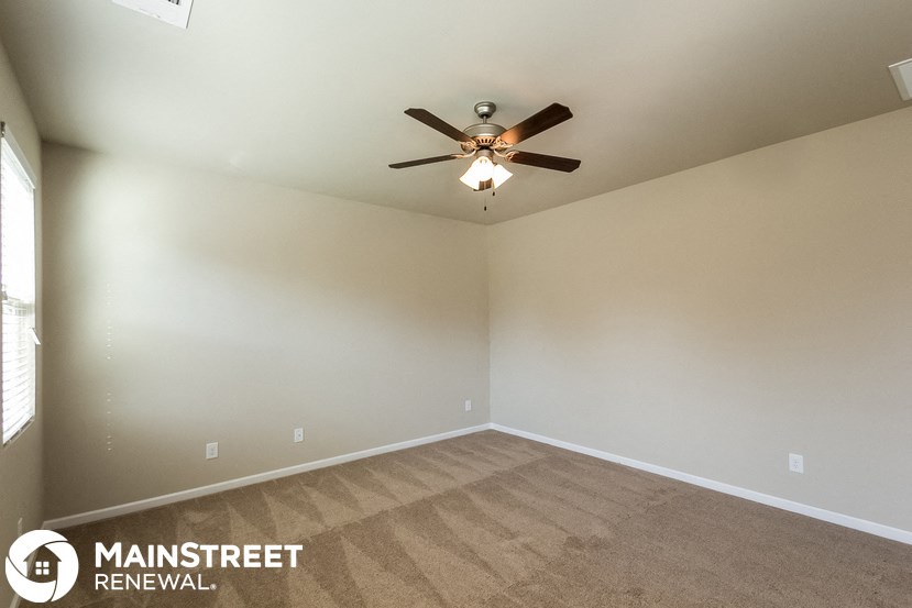 the living room of an empty home with a ceiling fan