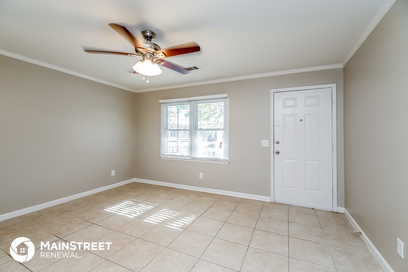 an empty living room with a ceiling fan