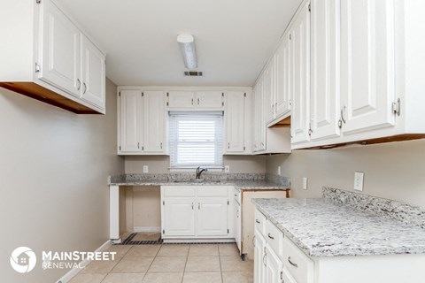 a kitchen with white cabinets and marble counter tops and a sink