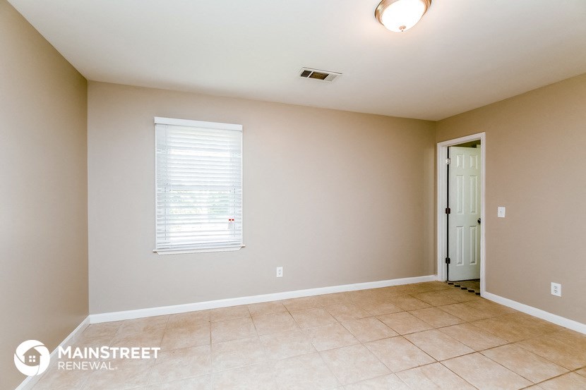 the spacious living room with tile flooring and a white door