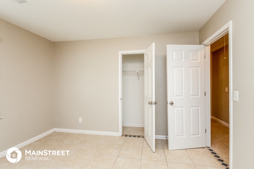 a room with two doors and a closet and a tiled floor