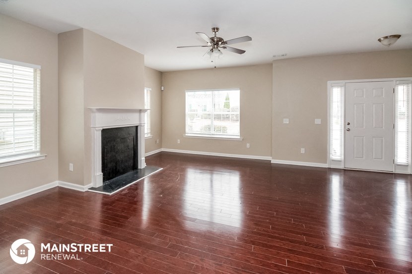 the living room with wood floors and a fireplace