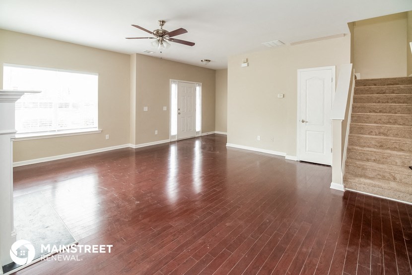 an empty living room with wood floors and a ceiling fan
