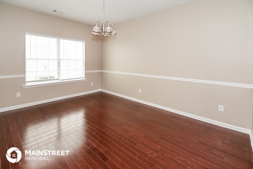 the living room of a home with wood floors and a window