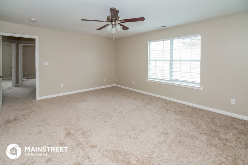 the master bedroom with carpeted floors and a ceiling fan
