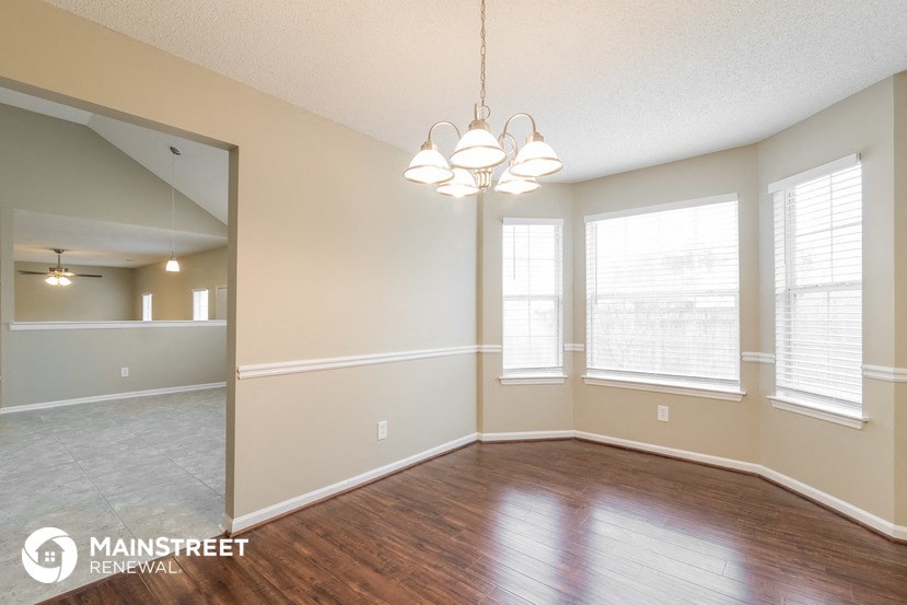 the living room and dining room of an empty house with wood flooring and windows