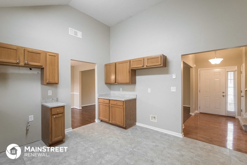 a kitchen and living room with wood cabinets and tile flooring