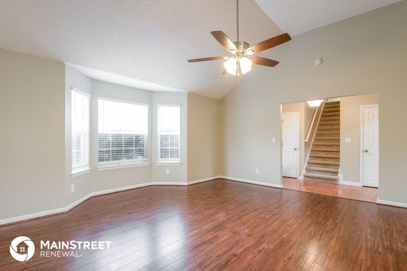 an empty living room with wood floors and a ceiling fan