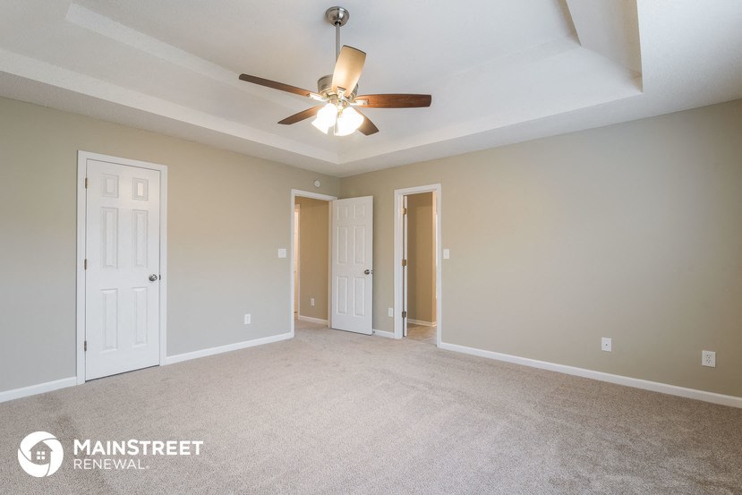 the living room of an empty home with a ceiling fan
