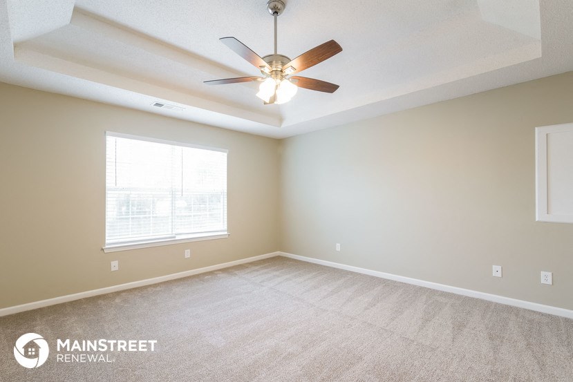 the living room of a new home with carpet and a ceiling fan