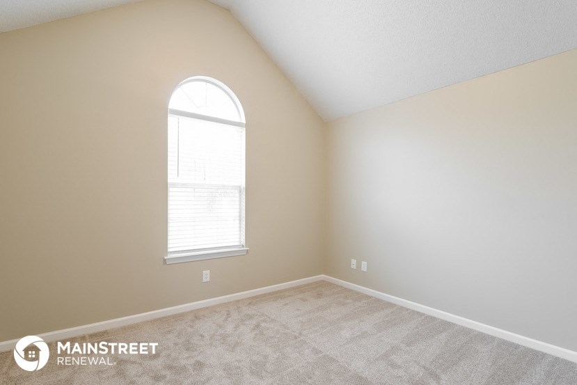the spacious living room of a home with a large window