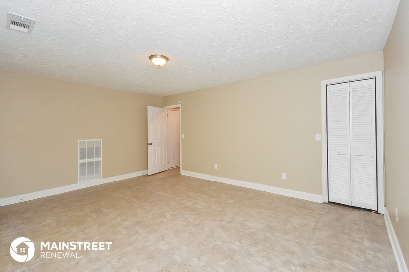 a spacious living room with beige carpet and a door to the dining room