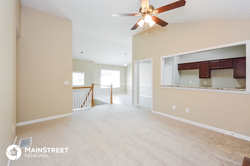 an empty living room with a ceiling fan