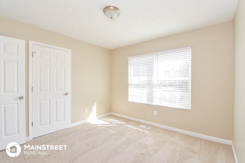 an empty room with a white door and a window