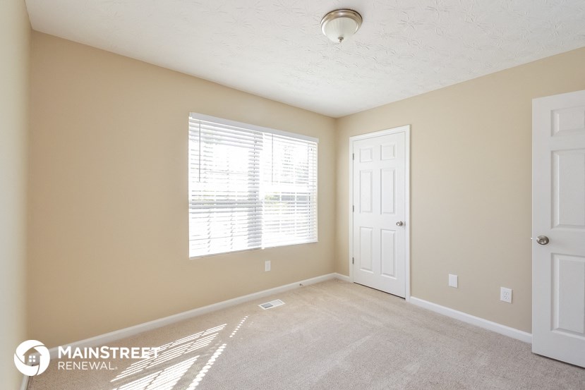 a bedroom with a door and a window and a carpeted floor