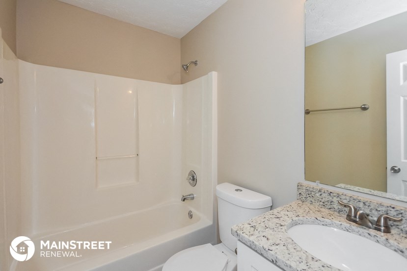 a bathroom with a toilet sink and tub and a mirror
