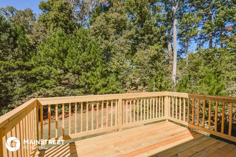 a deck with wooden railing and trees in the background