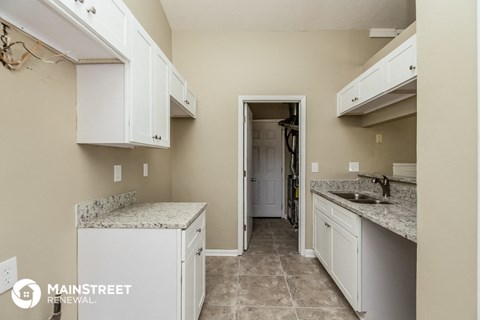 a kitchen with white cabinets and granite counter tops and a door to a hallway