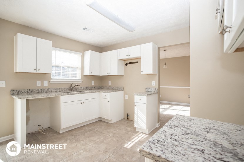 a large kitchen with white cabinets and granite counter tops