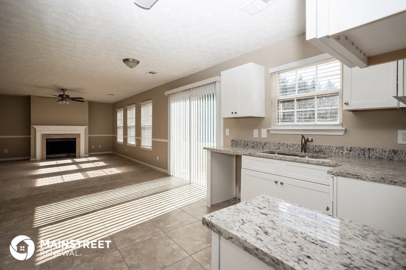 a kitchen and living room with a fireplace and marble counter tops
