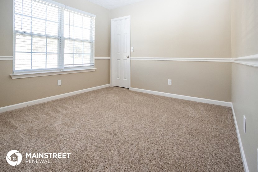 a room with a carpeted floor and a white door and window