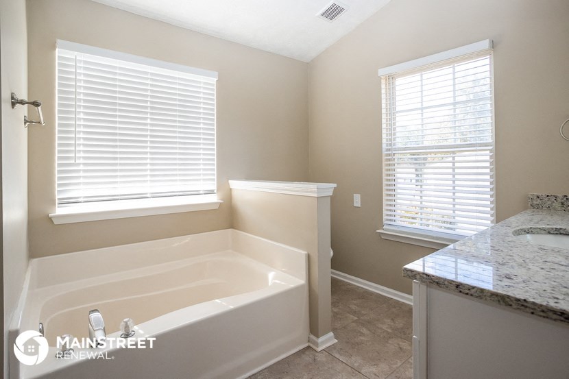 a bathroom with a tub and a sink and two windows