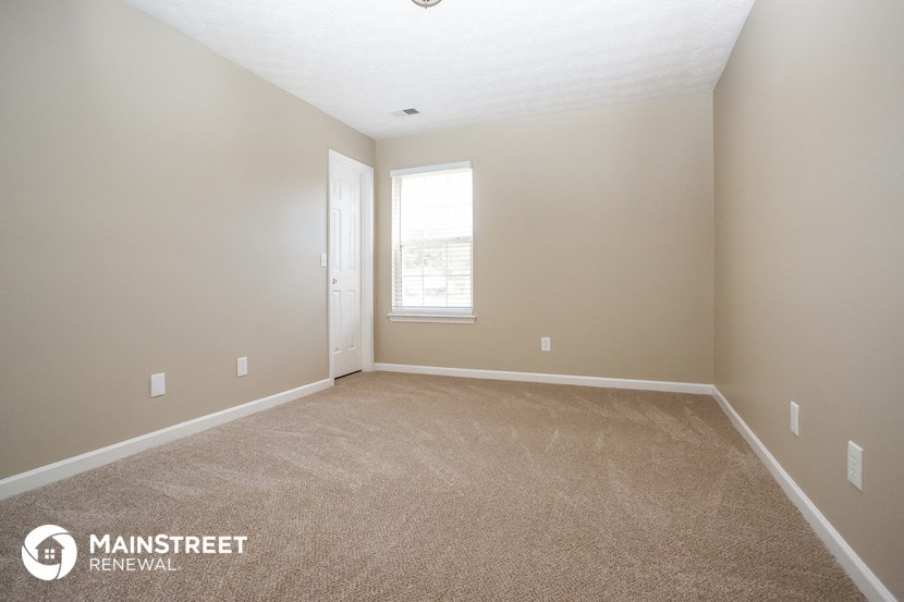 a large carpeted room with a window and a door