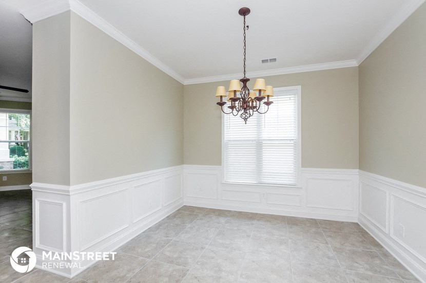 a dining room with white wainscoting and a chandelier