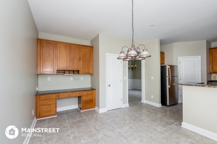 a kitchen with wooden cabinets and a desk and a refrigerator