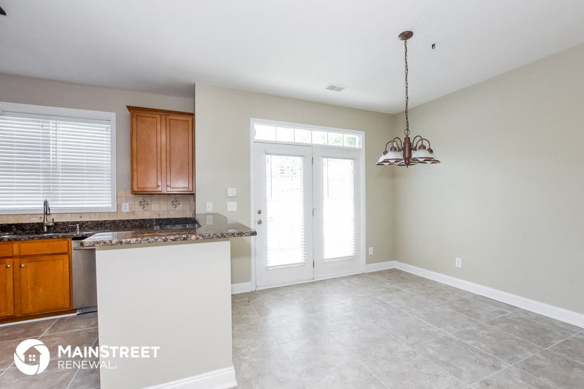 an empty kitchen and living room with a counter top and a door to a balcony