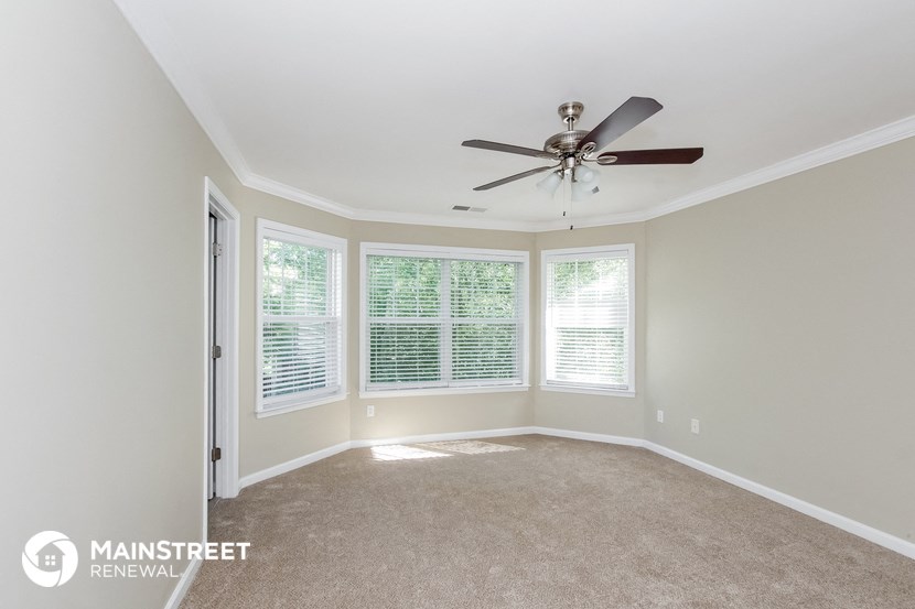 a living room with a ceiling fan and three windows