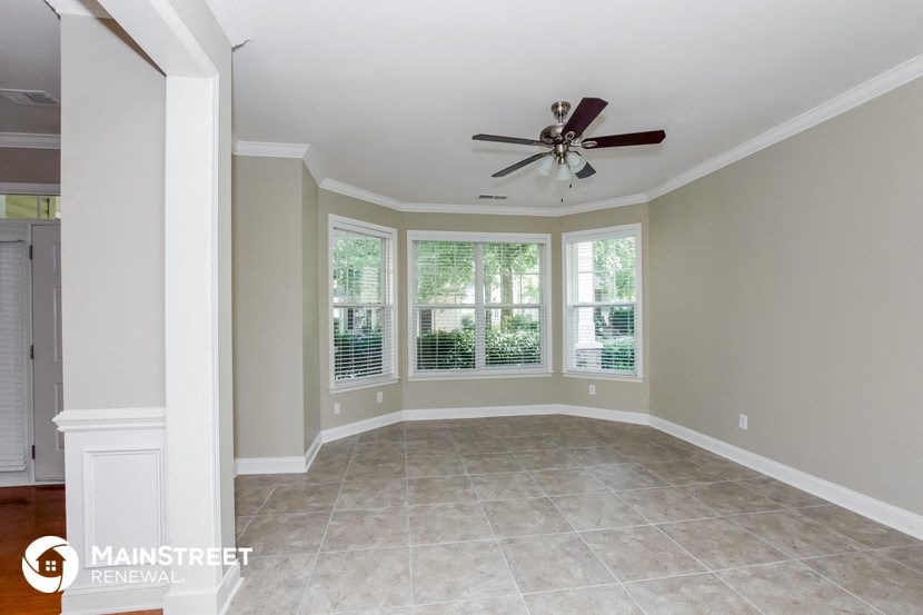 an empty dining room with a ceiling fan and windows