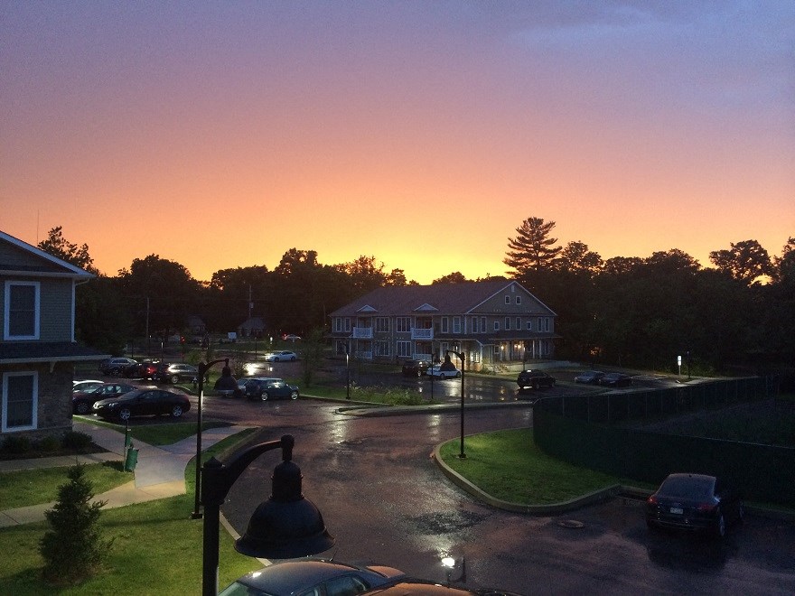 a sunset over a city street with cars and houses