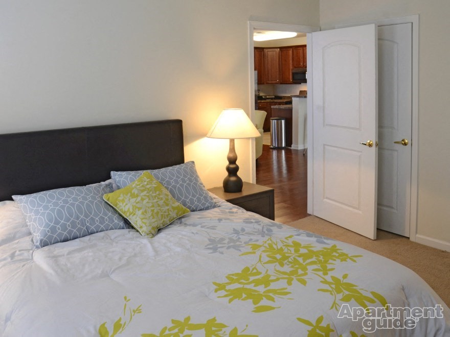 a bedroom with a bed and a door to a kitchen